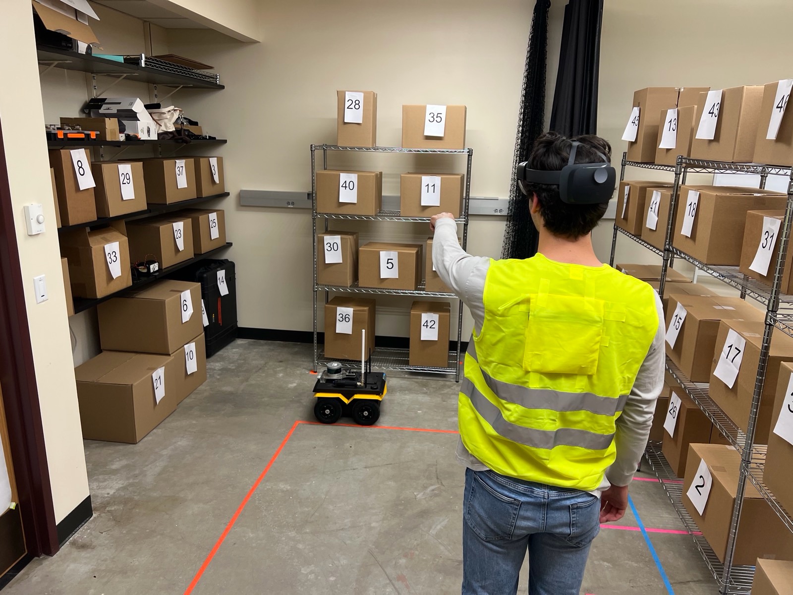 Participant wearing an AR headset spatially tasking a Jackal robot during an HRI study
